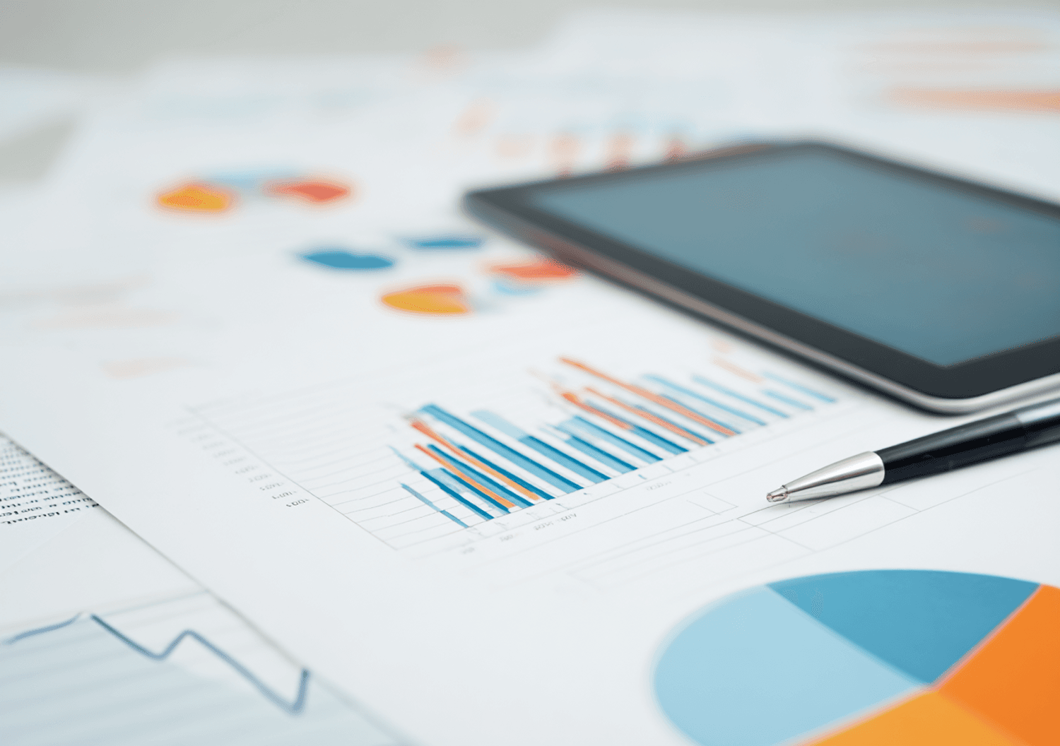 Colourful printed charts and graphs beside a pen and tablet